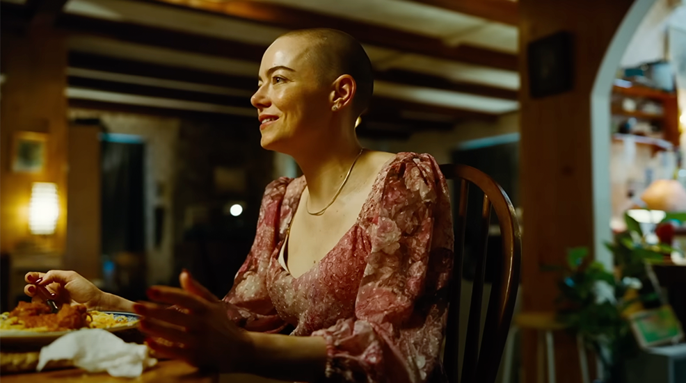 Emma Stone with a shaved head in still of Bugonia